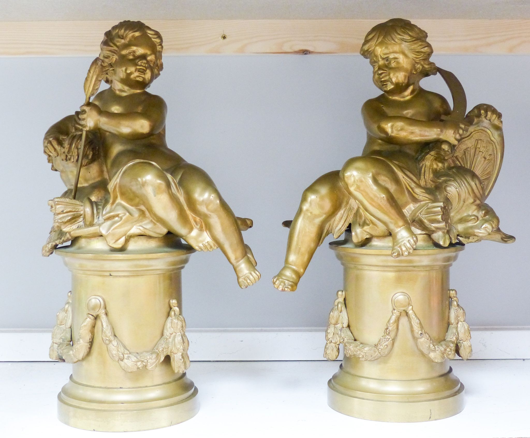 A pair of bronze figures of Cupid on circular pedestals, early 20th century, 42 cm high